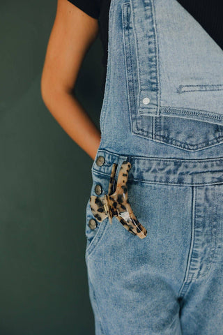 Person wearing blue denim overalls with a leopard print pocket square.