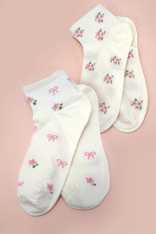 Pair of white socks with pink floral patterns on a pink background
