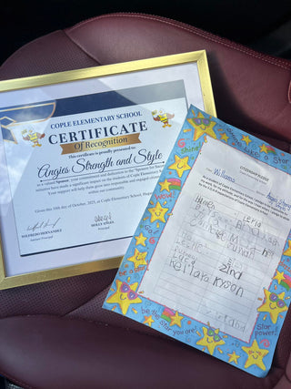 Cople Elementary School certificate of recognition and a child's drawing on a maroon surface.