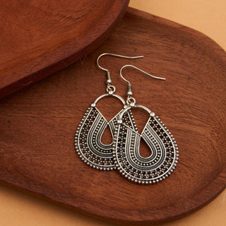 Textured silver earrings on a wooden surface
