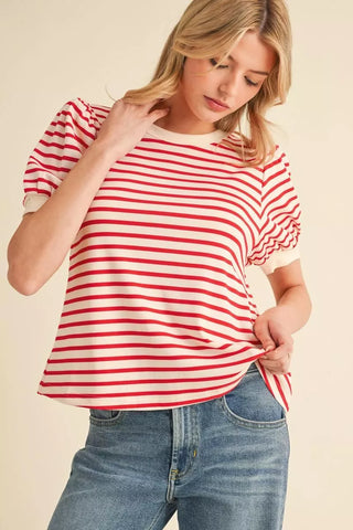 Woman wearing a red and white striped shirt with blue jeans on a beige background