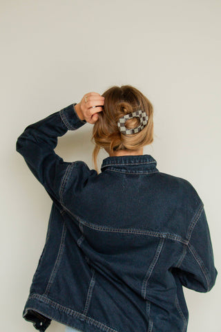 Person wearing a denim jacket with a plain background