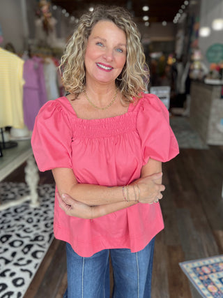 Woman wearing a pink blouse and blue jeans standing in a store.