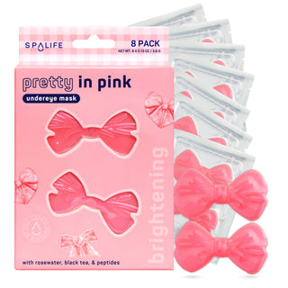 A pink box of SPALIFE Pretty In Pink Undereye Masks, shown with several individual packet packs fanned out behind it and two loose pink bow-shaped masks in front on a white background.