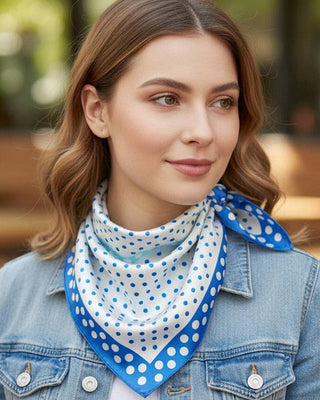 Woman wearing a blue and white polka dot scarf on a blurred outdoor background