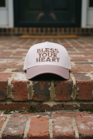 Cap with 'Bless Your Heart' text in ash and mocha colors on a brick step