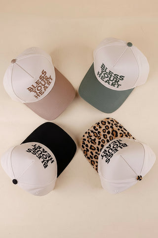 Five baseball caps with 'Bless Your Heart' text in various colors and patterns on a beige background.