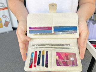 Person holding a beige wallet with cards and money