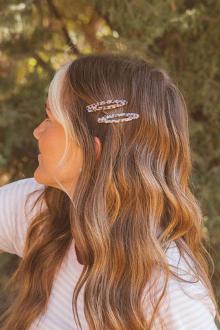 Person with wavy hair wearing a decorative hair clip outdoors