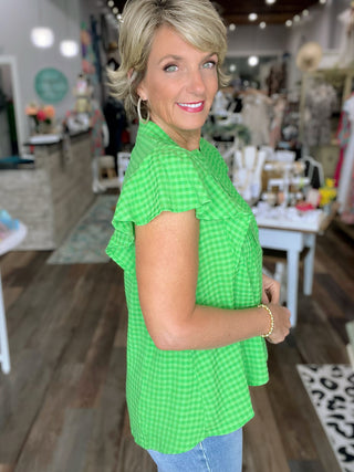 Woman wearing a green checkered blouse in a store setting