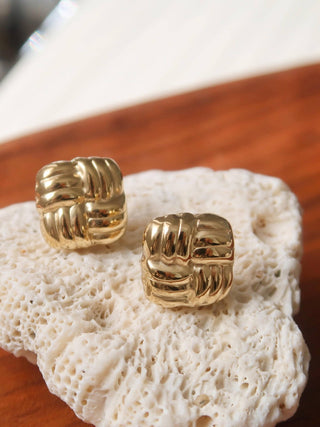 Gold earrings on a piece of coral