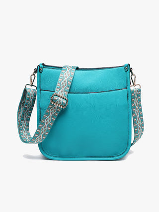 Turquoise handbag with a patterned strap on a white background
