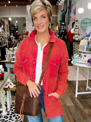 Woman in a red jacket standing in a store with various items and people in the background