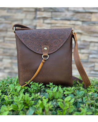 Brown leather bag with intricate design on a stone wall background