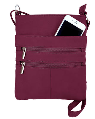 wine crossbody bag with multiple zippers and a phone inside on a white background