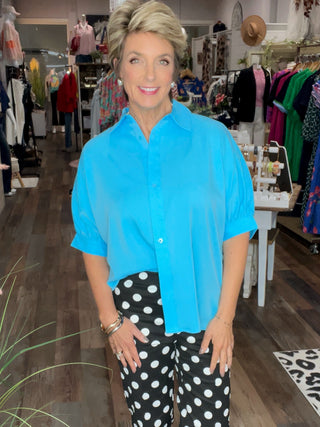 Woman in a blue shirt and polka dot pants standing in a store.