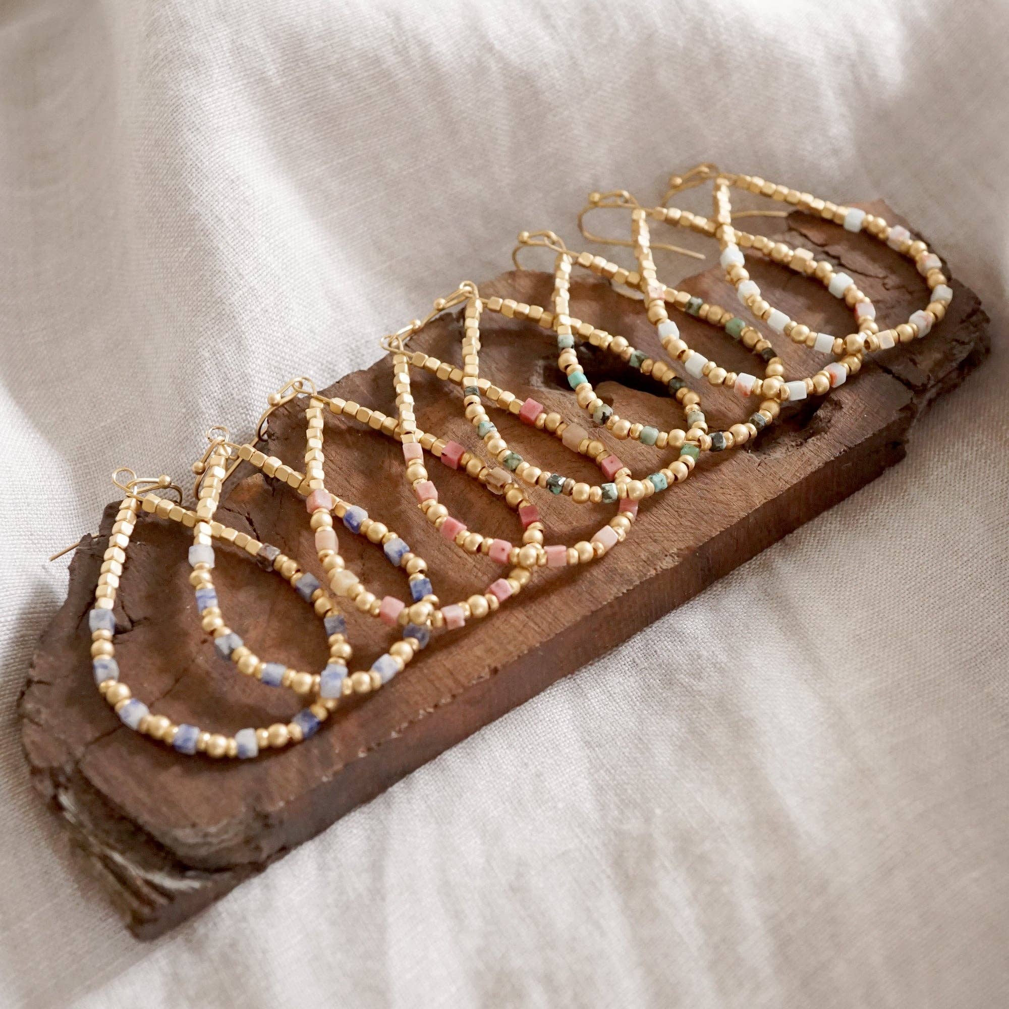 Beaded hoop earrings on a piece of wood with a neutral background