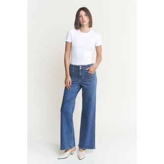 Woman wearing a white t-shirt and blue jeans on a plain background