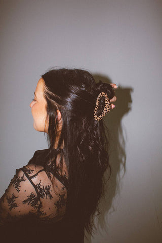 Woman with braided hair wearing a sheer black top against a plain background
