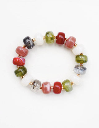 A beaded stretch bracelet featuring polished gemstone-like round beads in red, green, white, gray, and black, separated by small gold spacer beads, shown on a plain white background.