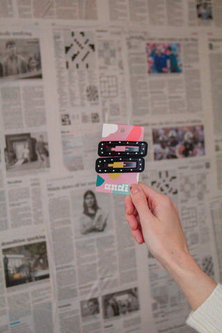 Hand holding a colorful card with text against a newspaper background