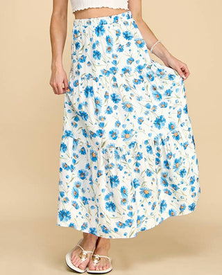Woman wearing a white top and blue floral skirt on a beige background