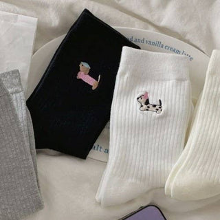 Black and white socks with embroidered dog designs on a white surface.