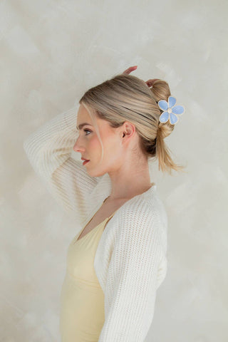 Woman with a floral hair clip against a neutral background
