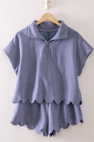 denim colored scalloped dress on a hanger against a white background