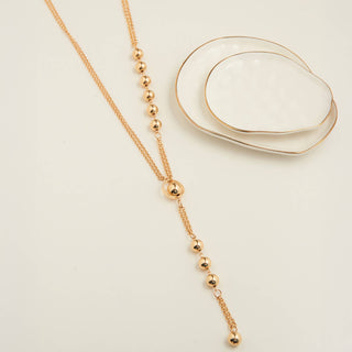 Gold cable chain Y beaded necklace on a light beige background