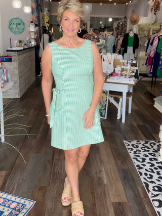 Woman in a green dress standing in a store with various items on display.