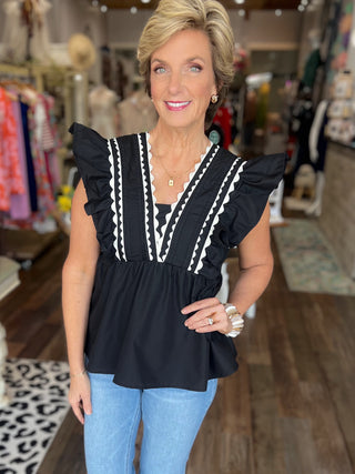 Woman wearing a black top with white trim in a store setting