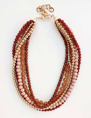 A multi-strand beaded necklace with alternating layers of faceted beads in deep red, warm brown, light pink, and metallic gold, finished with a gold lobster clasp, shown on a plain white background.