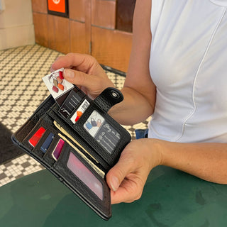 Person holding a black wallet with multiple card slots and a cash compartment.