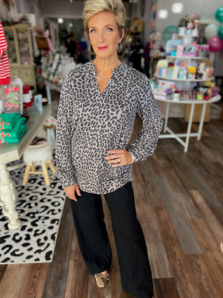 Woman wearing a leopard print blouse and black pants in a store setting