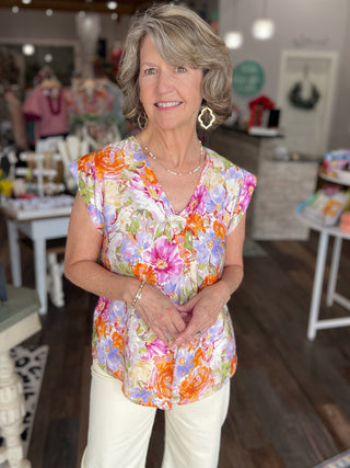 Woman wearing a colorful floral blouse in a store setting