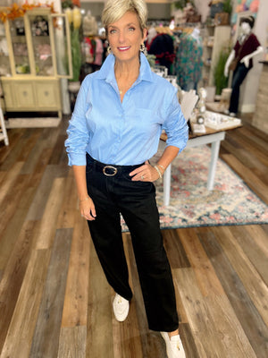 woman in blue button up and black barrel jeans