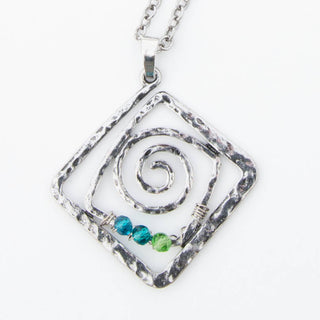 Silver pendant with spiral design and blue and green beads on a white background