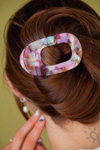 Multicolored hair clip in a person's hair against a green background