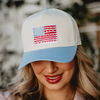 Woman wearing a cap with an American flag patch outdoors