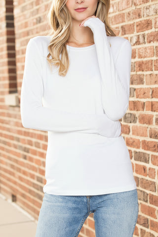 Woman wearing a white long-sleeve top and light blue jeans on a white background
