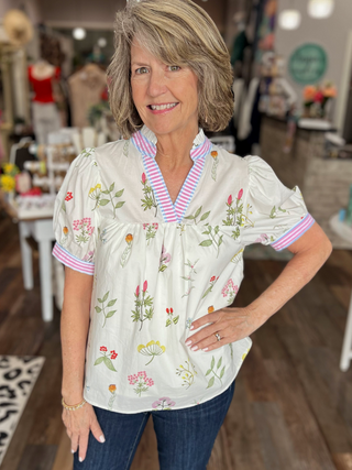 Woman wearing a floral blouse with a striped collar in a store setting
