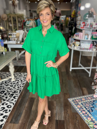 Woman in a green dress standing in a store with various items on display.