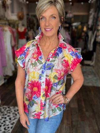Woman wearing a colorful floral blouse in a clothing store.