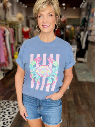 Woman wearing a blue t-shirt with a colorful crab design in a store setting
