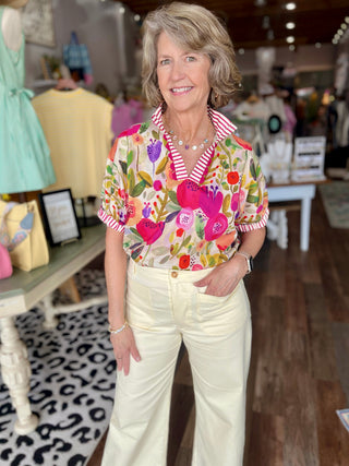 Woman wearing a colorful floral blouse and white pants in a store setting