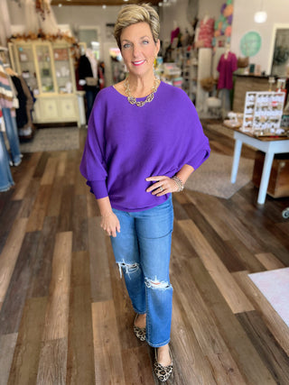 Woman in a purple sweater and blue jeans standing in a store.