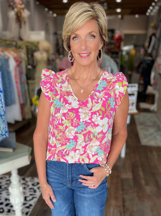 Woman wearing a pink floral top and blue jeans in a store setting