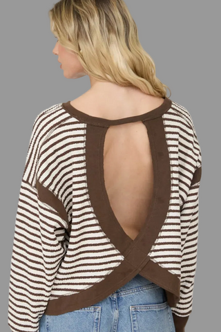 Woman wearing a striped sweater with open back design on a white background