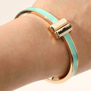 Gold and turquoise bangle on a wrist against a neutral background